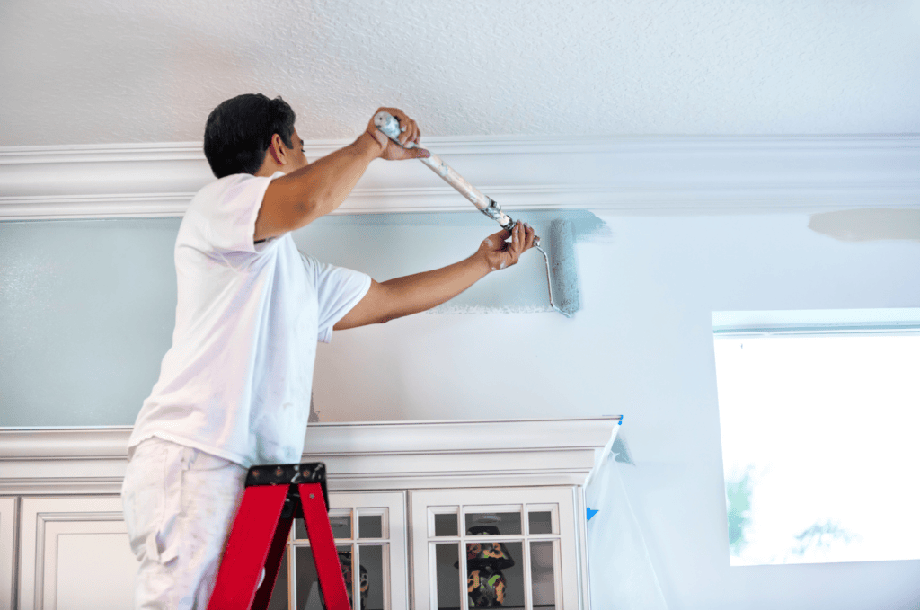 Professional home painter with brush and roller applying paint indoors.