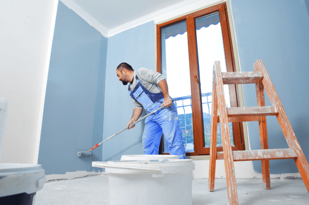 Professional painter using a roller to paint a large wall evenly.